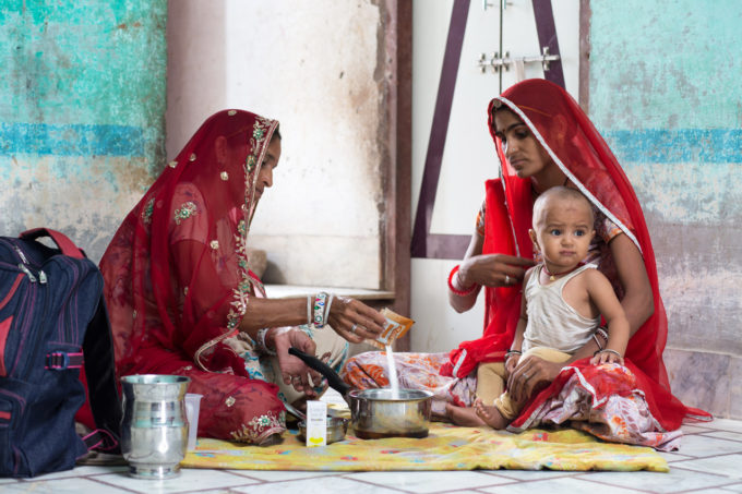 twee vrouwen met baby bereiden voedsel in India