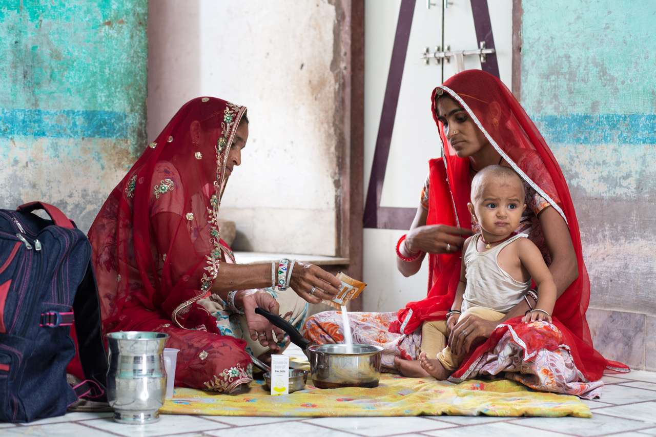 twee vrouwen met baby bereiden voedsel in India